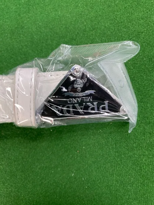 P-shaped silver buckle with white belt on black background